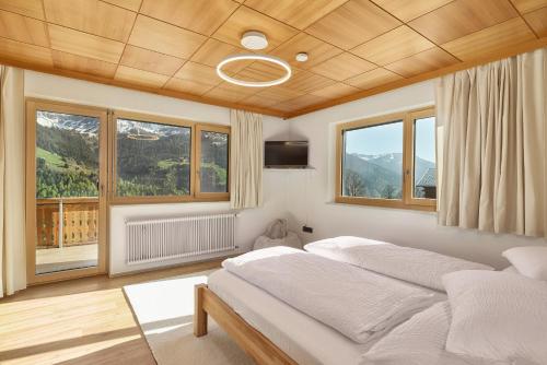a bedroom with two beds in a room with windows at Großes Bergapartment 4 SZ Balkon & Aussicht in Sonntag