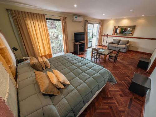 a bedroom with a large bed and a living room at Hotel Los Sauces in Cafayate
