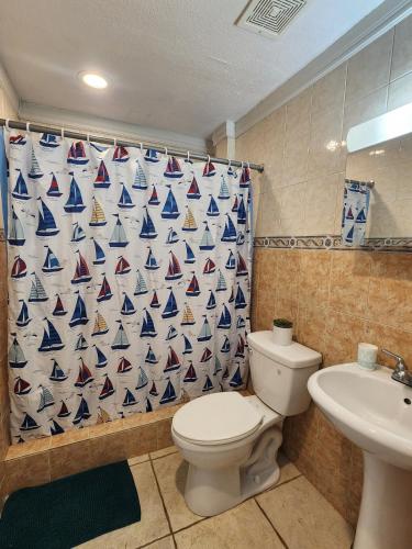 a bathroom with a shower curtain with a toilet and a sink at Vista Azul Apartment in Punta Santiago