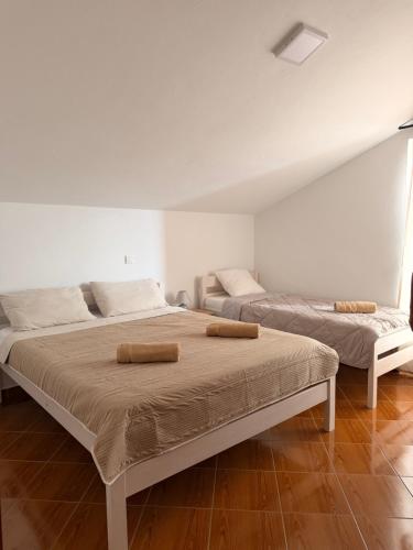 two beds in a white room with two bedsvisor at Apartmani Gržeta in Vir