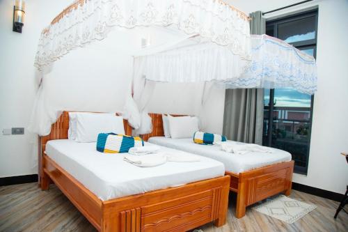 two twin beds in a room with a window at CHAMBO VILLAS in Morogoro