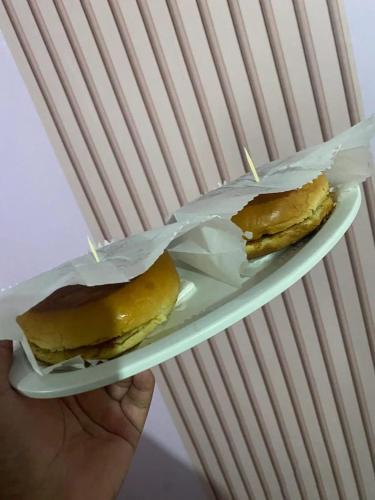 a person holding a plate with two pastries on it at Hotel São Mateus in São Paulo