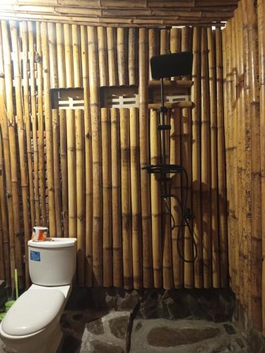 a bathroom with a toilet in front of a bamboo wall at A2 Coconut in Pulau Sarang