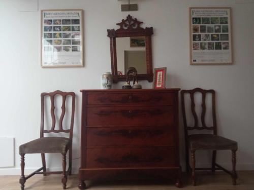 a dresser with two chairs and a mirror on a wall at Can Perles casa rural in Tárbena