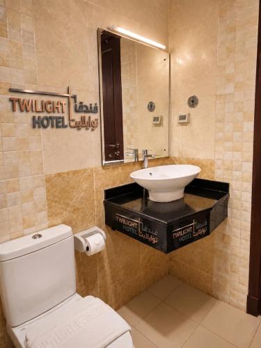 ein Badezimmer mit weißer Toilette und Waschbecken in der Unterkunft Twilight Hotel Al-Hail in Muscat