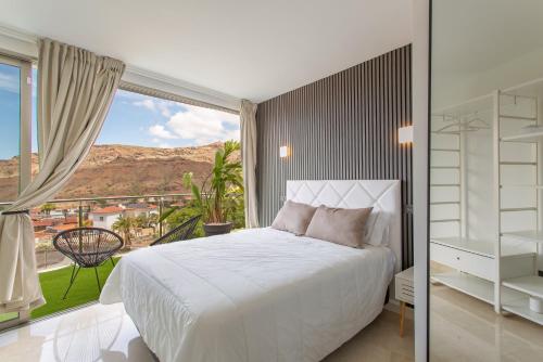 a bedroom with a white bed and a large window at Villa Coco in Mogán