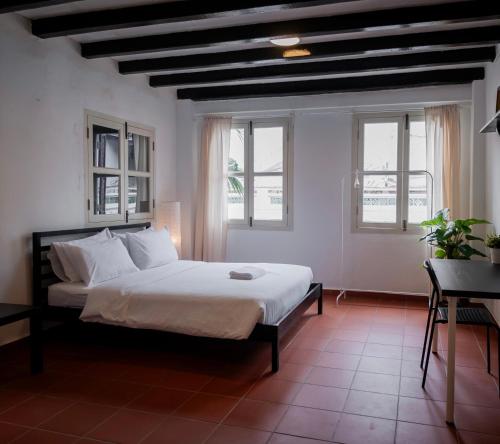 a bedroom with a bed with white sheets and windows at Aayu Church St - 7 mins to Esplanade, George Town in George Town