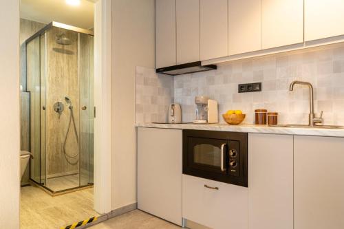 a kitchen with white cabinets and a sink and a shower at L anima II in Skiathos