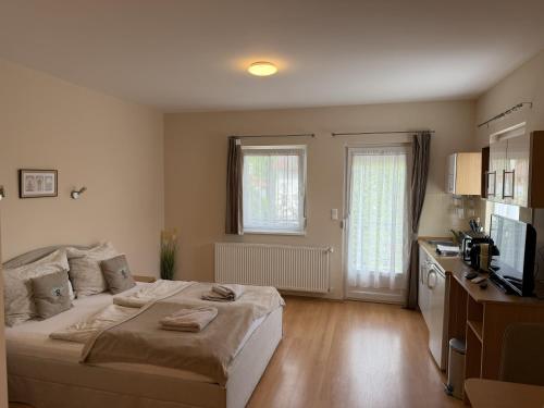 a bedroom with a large bed and a kitchen at Akácfa B&B in Zalakaros