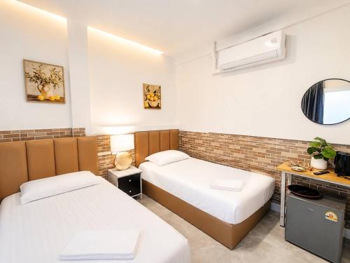 a hotel room with two beds and a mirror at Ruenthip Homestay in Bangkok
