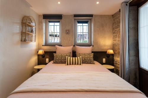 a bedroom with a large bed with two windows at La CHARMILLE PADIRAC in Padirac