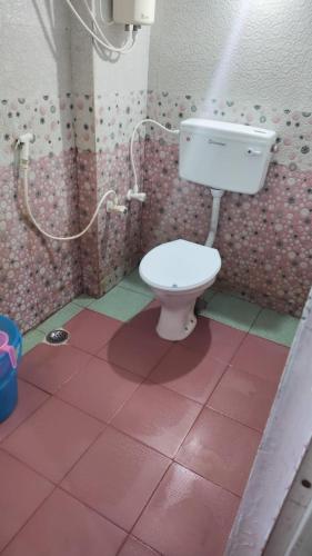a bathroom with a toilet and a pink tile floor at natchiyar home stay in Rāmeswaram
