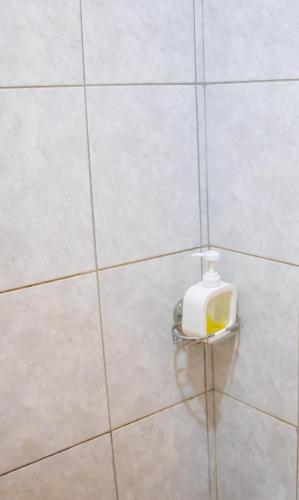 a bathroom with a soap dispenser on a tiled wall at HIDEOUT BnB with swimming pool in Kiambu