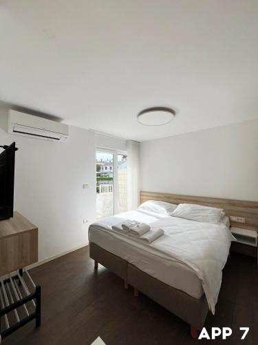 a bedroom with a bed with white sheets and a tv at Casa Maly in Portorož