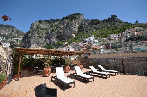 a patio with lounge chairs and a view of a mountain at Hotel L'Antico Convitto in Amalfi
