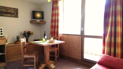 a living room with a table and a tv at Résidence Le Chamois d'Or in Val Thorens