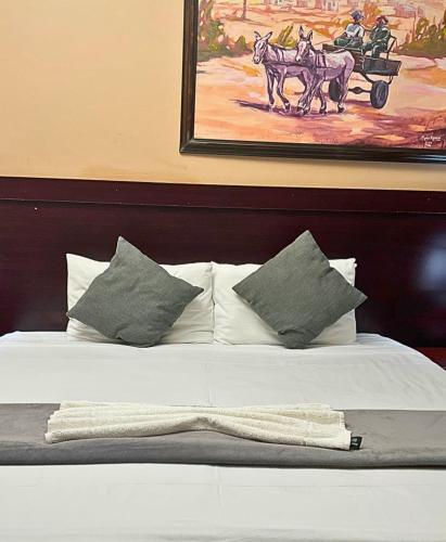 a bed with pillows and a painting of a horse drawn carriage at River-Ridge Guest House in Gaborone