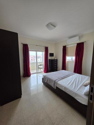 a bedroom with a large bed with red curtains at Vendome in Paceville