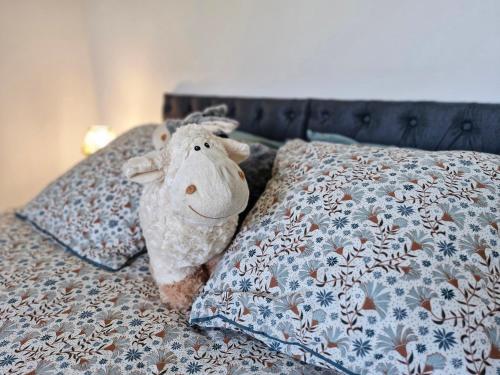 a stuffed sheep laying on a bed with pillows at Le Clos des Elfes - suite climatisée in La Roque-Gageac