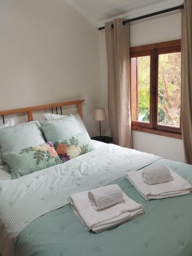 a bed with two towels on it with a window at Quinta Meneses in Santa Cruz