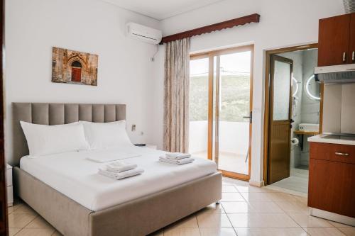 a bedroom with a large white bed and a balcony at Vila Malo in Ksamil