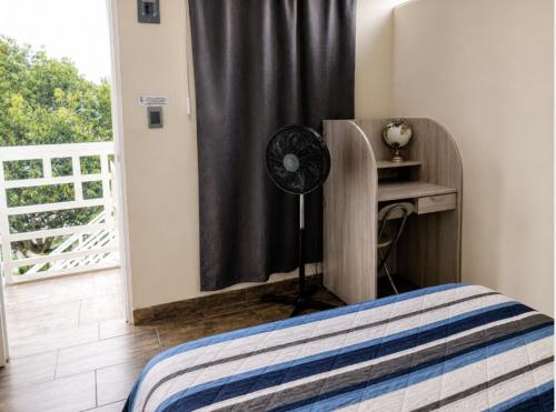 a bedroom with a bed and a fan next to a window at Rose Room, Paseo Durango in Durango