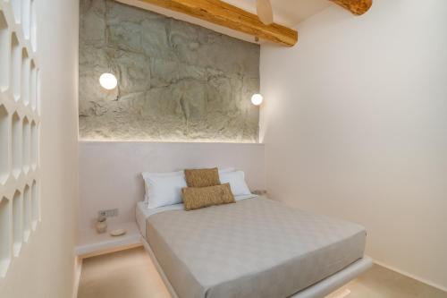 a small bedroom with a bed and a stone wall at Pnoé Lounge Suite in Mandrakia