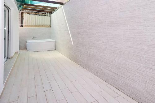 a bathroom with a white tub and a white tile wall at Kai Guest House in Polychrono