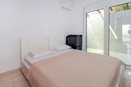 a white bedroom with a bed and a window at Kai Guest House in Polychrono