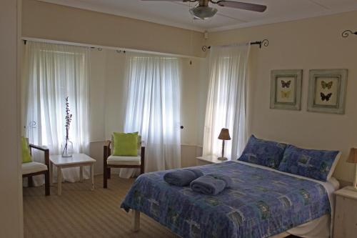 a bedroom with a blue bed and two windows at Ons Kraal in Franskraal