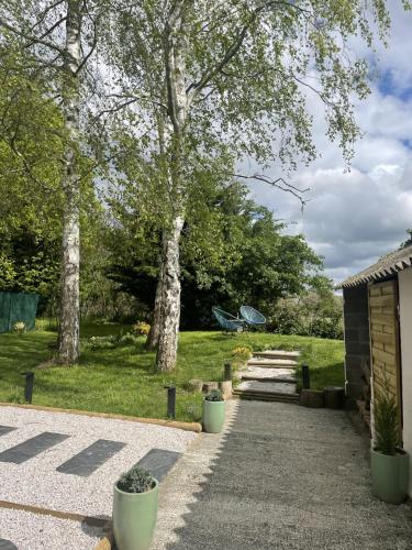 a walkway with trees and a bench in a park at L'Escale d'Omaha - Cottage de 50m2 in Saint-Marcouf
