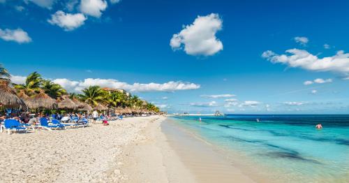 a beach with people sitting in chairs and the ocean at Hotel Marina El Cid Spa & Beach Resort - All Inclusive in Puerto Morelos