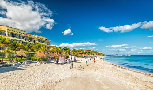 a beach with umbrellas and the ocean on a sunny day at Hotel Marina El Cid Spa & Beach Resort - All Inclusive in Puerto Morelos