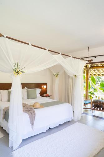 a bedroom with a white bed with a canopy at Villa dos Corais in Morro de São Paulo