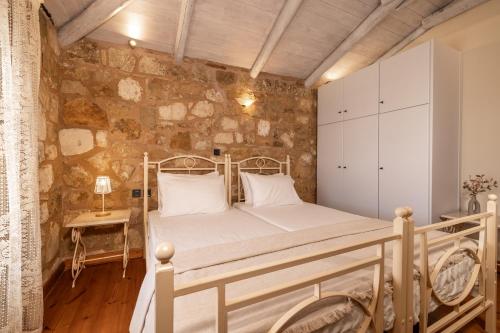 a bedroom with a bed and a stone wall at Artemis Luxury Villa in Méson Yerakaríon