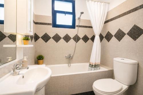 a bathroom with a tub and a toilet and a sink at Villa Driftwood in Rhodes Town