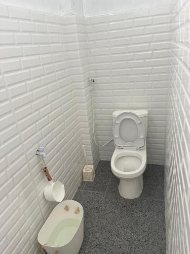 a white bathroom with a toilet and a scale at Nok Homestay in Pangururan