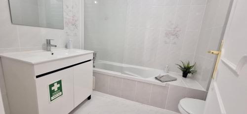 a white bathroom with a sink and a tub and a toilet at Maré Viva in Quarteira