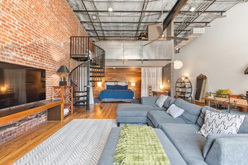 a living room with a blue couch and a brick wall at Industrial Modern Loft in Downtown Lafayette in Lafayette