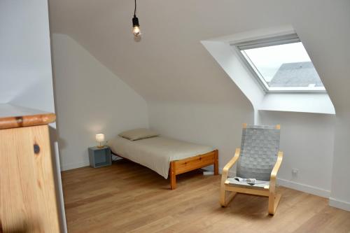 a bedroom with a bed and a chair and a window at Maison de plage in Guissény