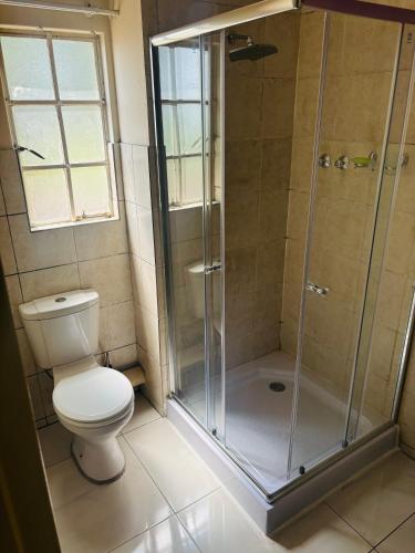 a bathroom with a toilet and a glass shower at Sleep in Crestwave villas in eMalahleni