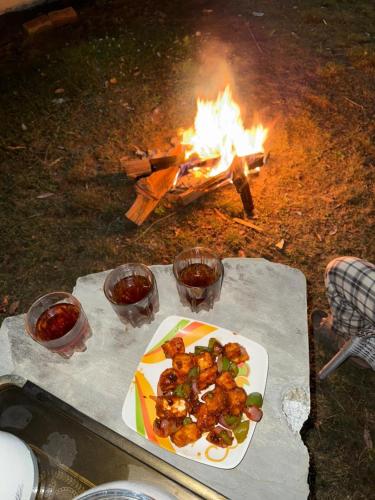 a plate of food on a table next to a fire at vishwaram Homestay in Chail