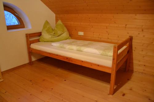 a small bed in a room with a wooden wall at Sunnaschi Appartements - Wohnungen oder gesamt als "Hütte" in Laterns