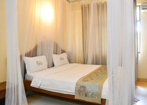 a bedroom with a bed with white curtains at Two Oceans Hotel Voi in Voi