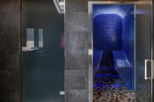 a shower with a glass door with a blue tile floor at The Damson Barn in Biddulph