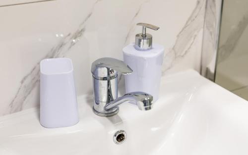 a bathroom sink with a faucet and a soap dispenser at Apartman Srebrni Horizont in Veliko Gradište
