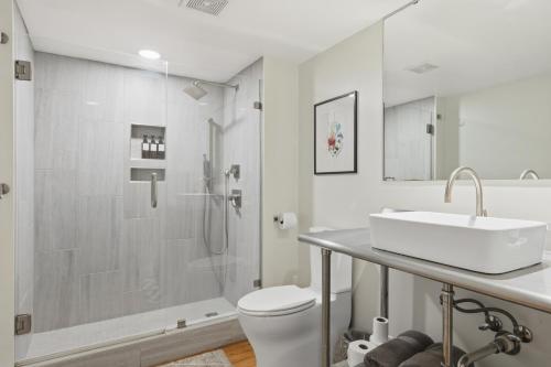 a white bathroom with a sink and a shower at Industrial Modern Loft in Downtown Lafayette in Lafayette
