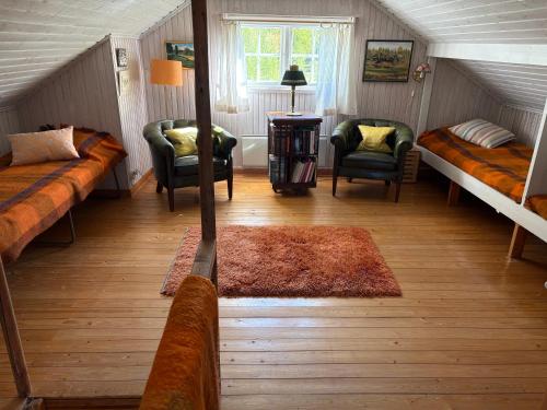 a attic room with two beds and two chairs at Mosters hus in Gansbyn
