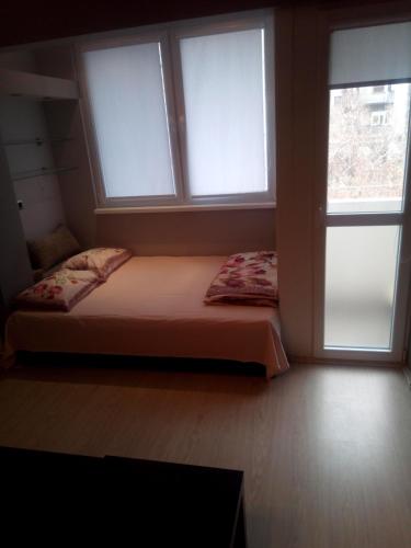a bed sitting in a room with two windows at Apartment Nenov in Skopje