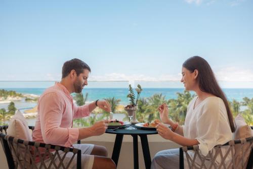 a man and a woman sitting at a table eating food at Dreams Aventuras Riviera Maya - All Inclusive in Puerto Aventuras